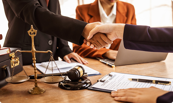 Professionals shaking hands over a scales of justice and legal gavel.  