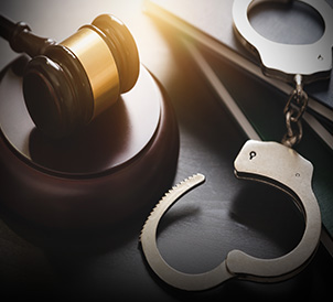 Handcuffs and a wooden gavel representing criminal defense law services.