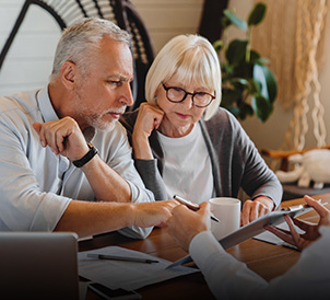A senior couple reviewing legal documents with an expert for estate planning.