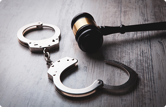 Handcuffs and a wooden gavel on Wooden Table representing criminal defense law services.