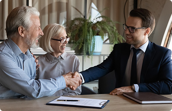 Senior couple shaking hands with a legal professional to discuss wills and estate planning.