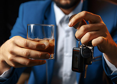 A person holding a glass of whiskey and car keys, representing a DUI legal case.